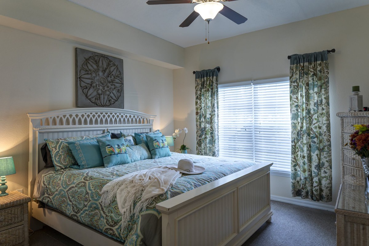 A cozy bedroom with a large bed, decorative pillows, and natural light coming through the window.