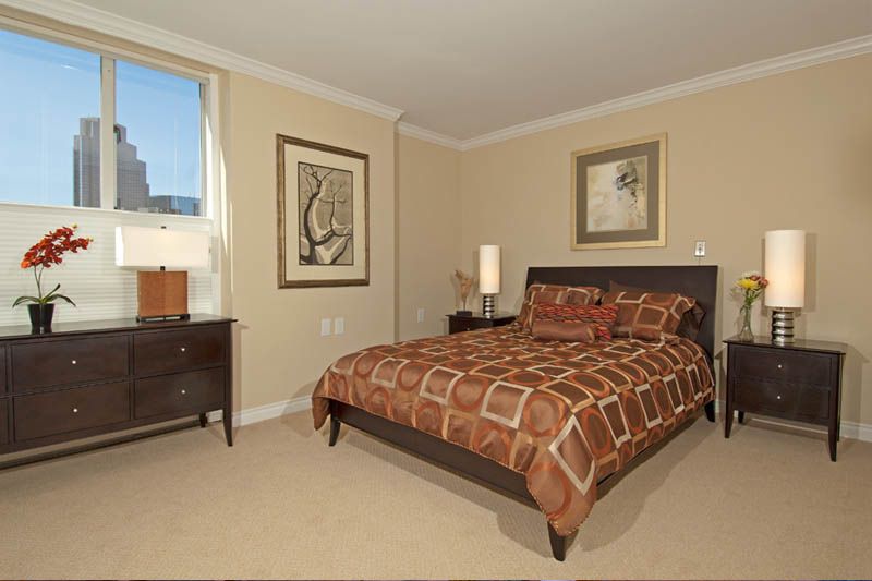 A cozy bedroom featuring a patterned bedspread, artwork on the walls, and elegant furniture.