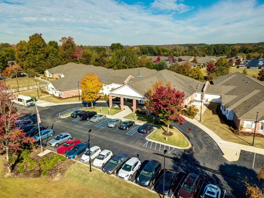 Aerial view of a building surrounded by a parking lot and autumn trees.