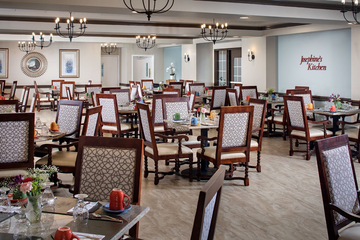 An elegant restaurant dining area with neatly arranged tables and chairs beneath decorative chandeliers.