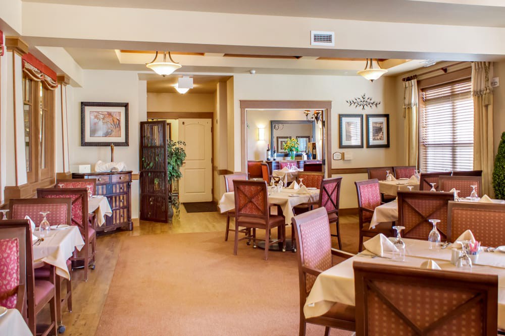 A warmly lit restaurant dining area with neatly arranged tables and chairs.