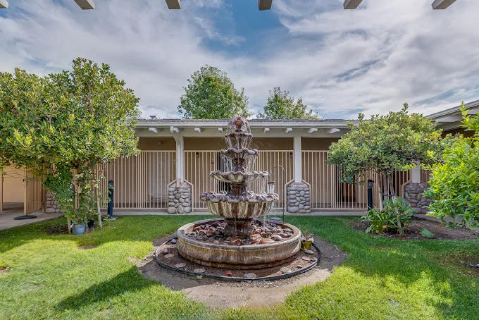 A tranquil courtyard with a multi-tiered fountain surrounded by lush greenery.