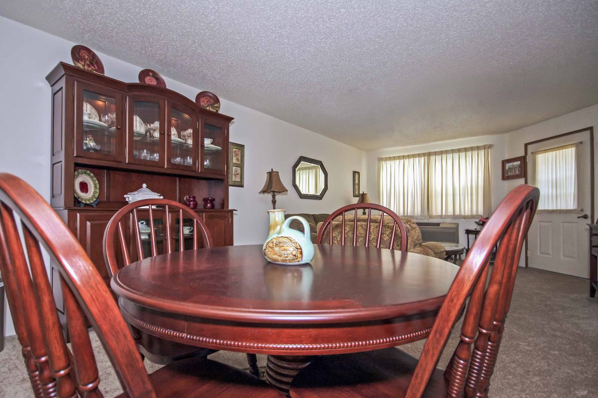 A cozy dining room featuring a wooden table and chairs, with a cabinet and decorative items.