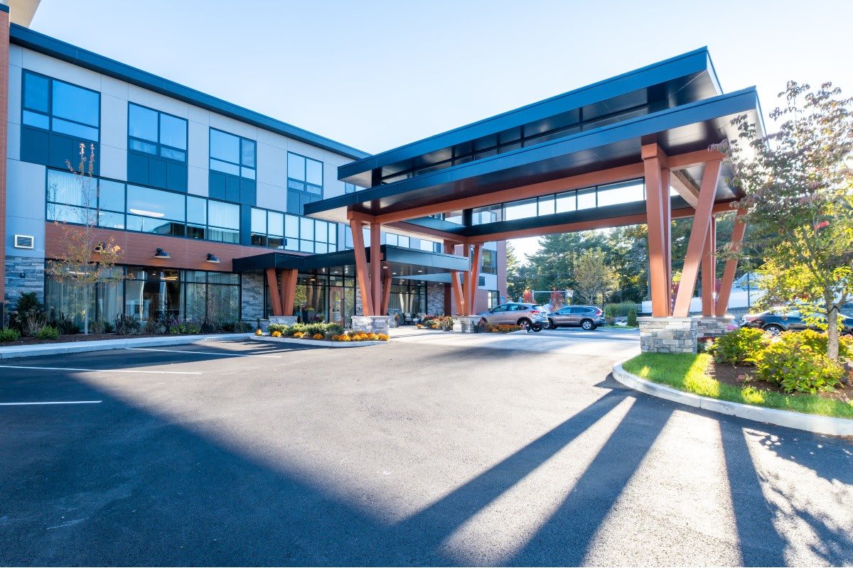 A modern hotel entrance with a covered driveway under a clear blue sky.