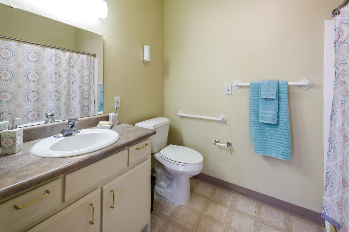 A clean and simple bathroom with a sink, toilet, and blue towels.