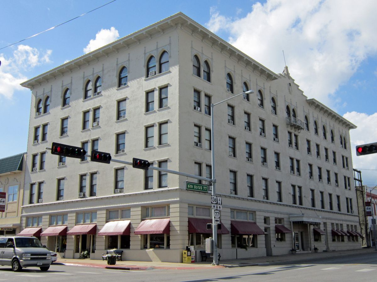 A historic multi-story building located at a street corner, featuring numerous windows and awnings.