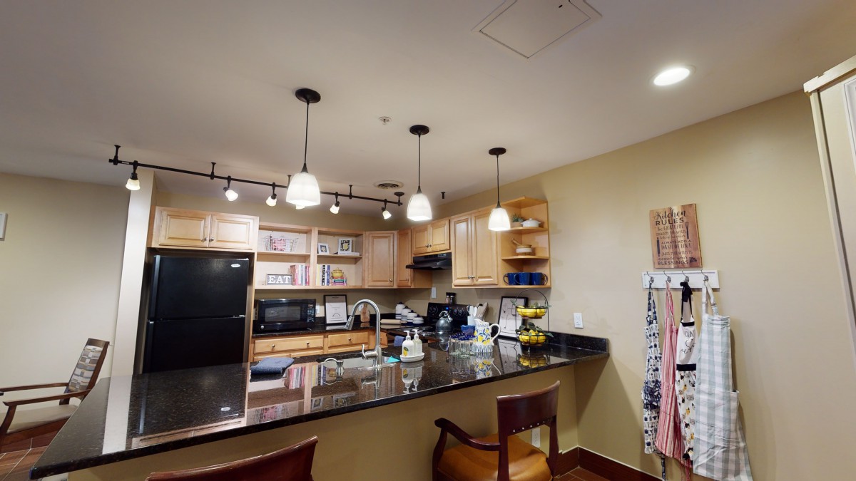 A modern kitchen with wooden cabinets, granite countertops, and pendant lighting.