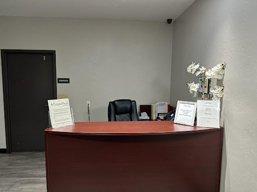 A quiet reception area with a wooden desk, comfortable chair, and decorative flowers.