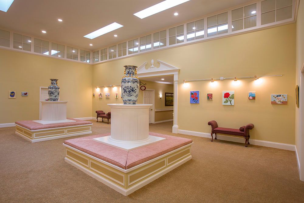 A well-lit art gallery interior featuring sculptures and colorful paintings on display.