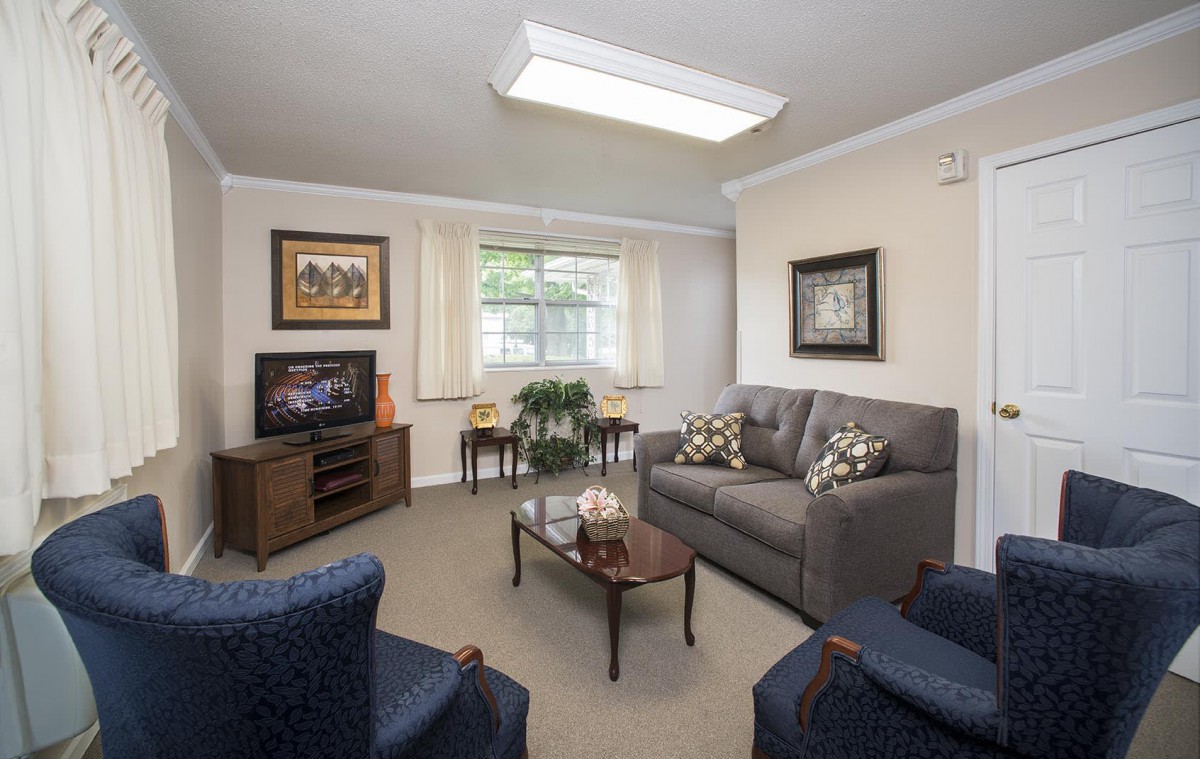A cozy living room with a sofa, armchairs, and a television.
