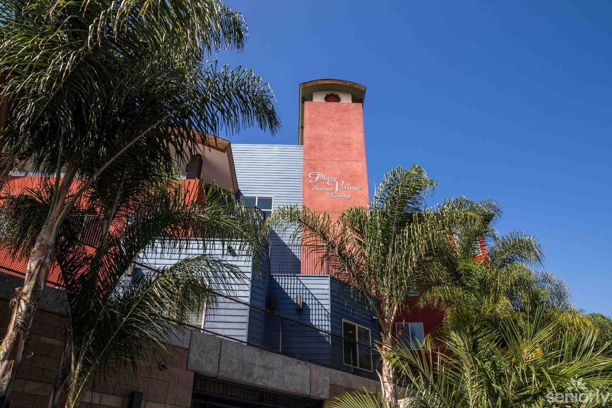 A modern urban building with colorful exterior and palm trees against a clear blue sky.