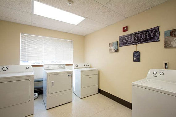 A well-lit laundry room with washing machines and dryers.