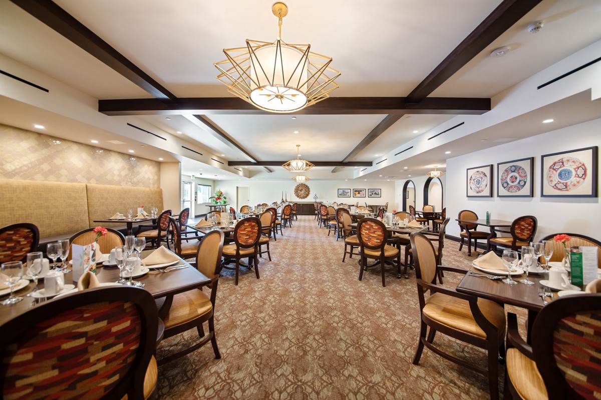 An elegant and spacious dining room with neatly arranged tables and chairs, featuring a decorative chandelier.
