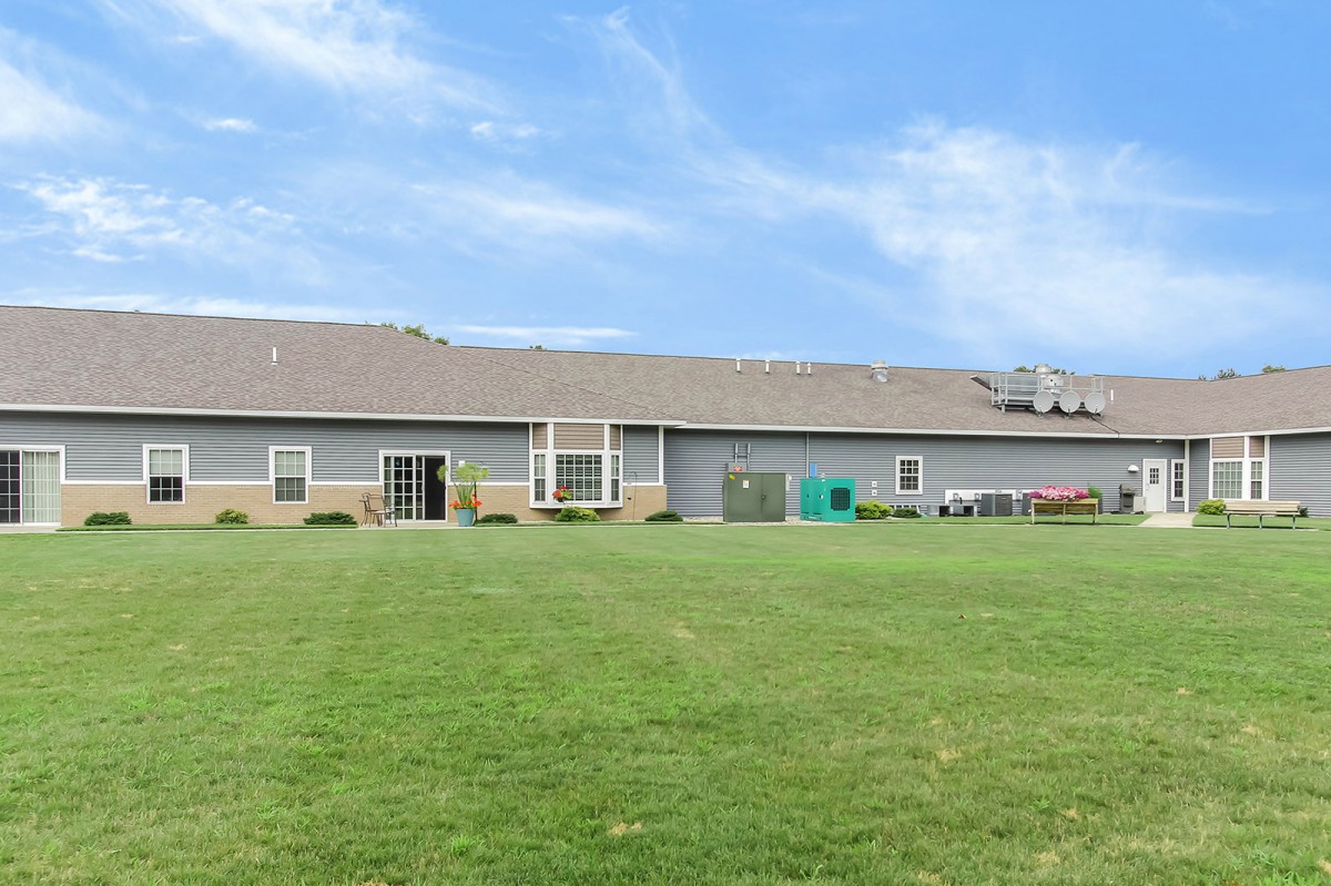 A spacious backyard with a well-kept lawn behind a single-story house on a cloudy day.