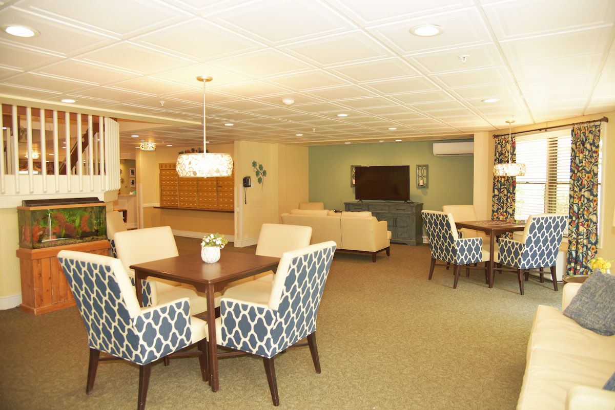 A spacious living area with dining tables, comfortable seating, and a television.