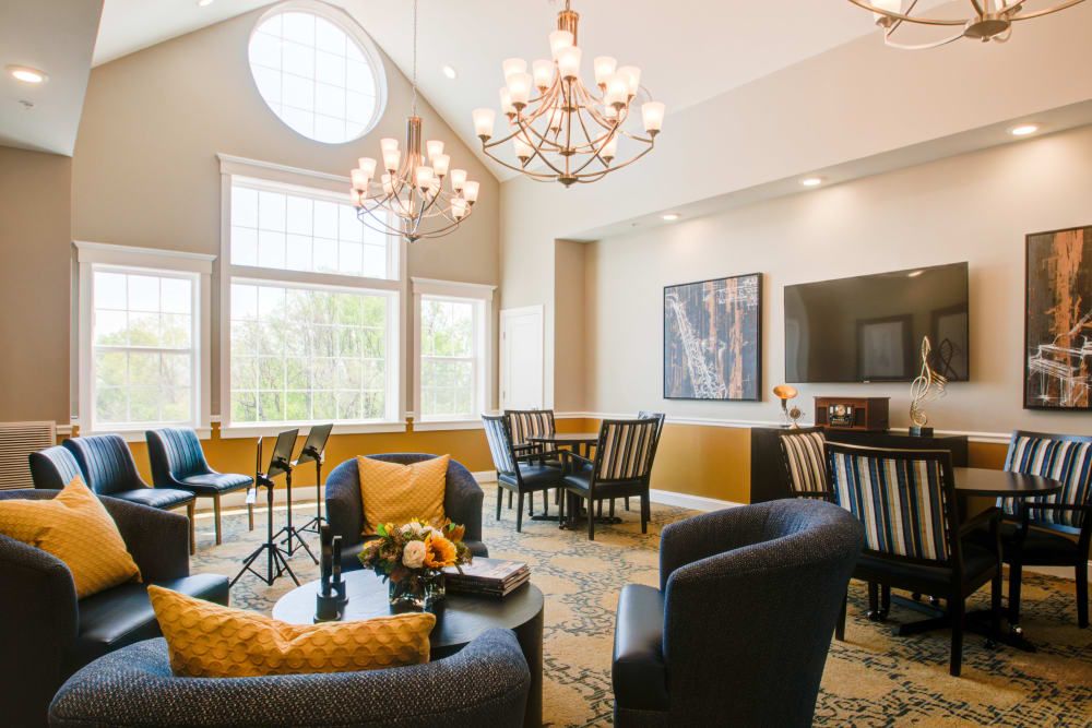 A stylish living room with elegant chandeliers, comfortable seating, and large windows.