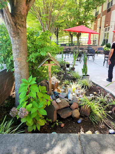 A serene garden area featuring greenery, decorative rocks, and seating in the background.