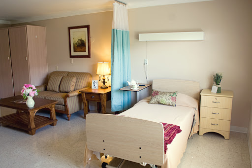 A well-lit, comfortable hospital room featuring a patient bed, a sofa for visitors, and a cozy ambiance.