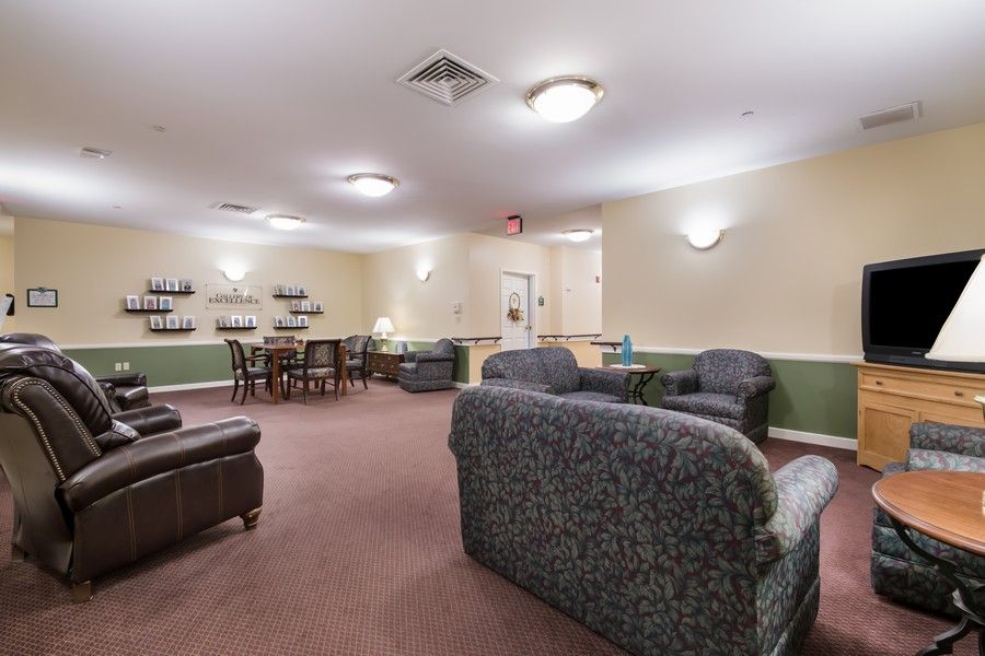 A cozy living room with comfortable sofas, chairs, and a dining table under soft lighting.