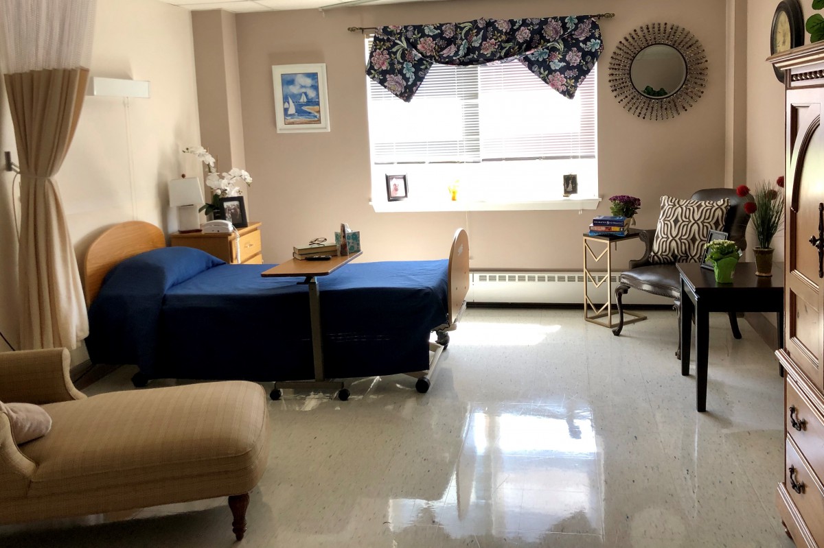 A bright and neatly arranged bedroom with a hospital bed by the window.