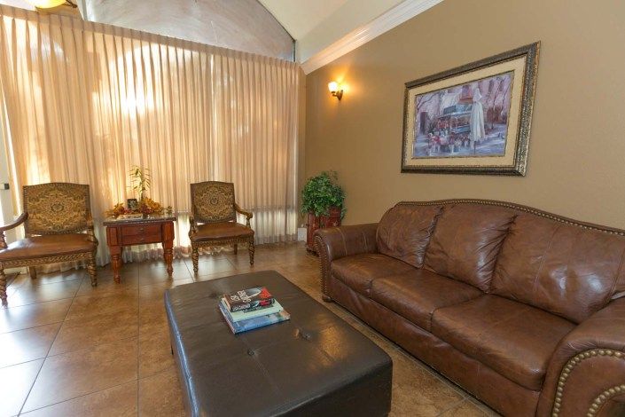 A cozy living room with a leather sofa, coffee table, and comfortable chairs by the window.