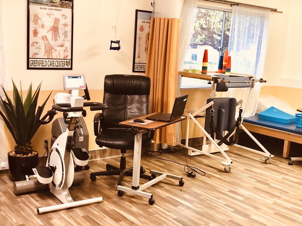 A physical therapy clinic featuring exercise equipment and a workspace setup.