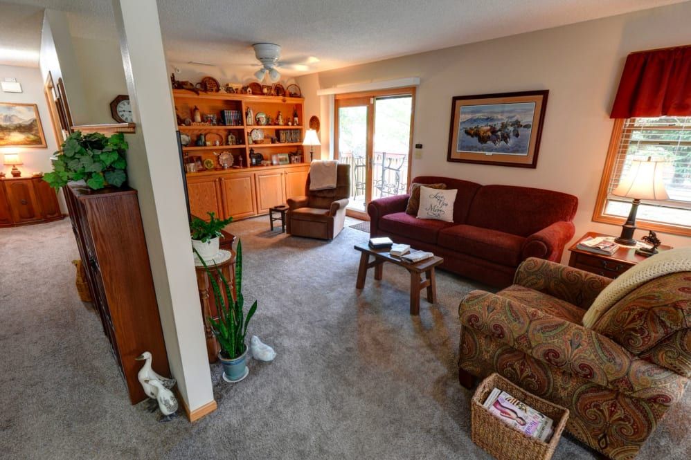 A cozy living room featuring a sofa, armchair, and a bookshelf filled with decor.