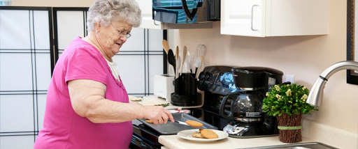 An elderly woman skillfully prepares cookies in her cozy kitchen.