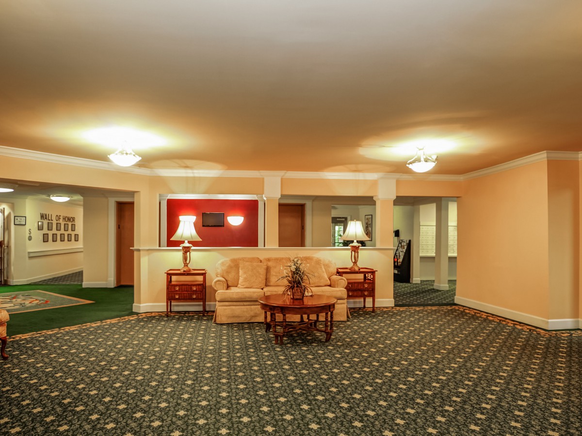 A warmly lit hotel lobby with a central seating area featuring a sofa and side tables.
