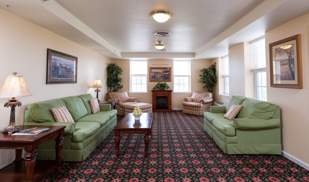 A cozy living room with green sofas, floral carpet, and a fireplace.