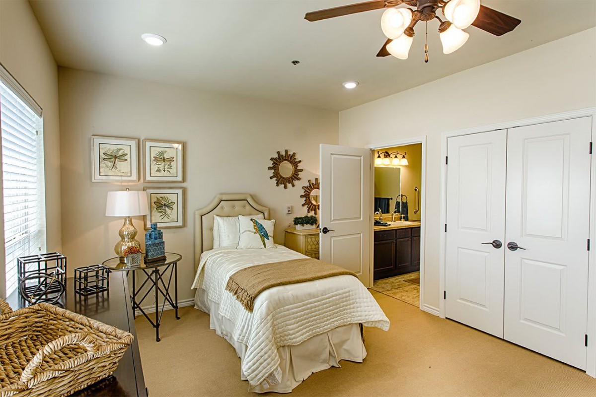 A cozy bedroom with a single bed, wall art, and warm lighting.
