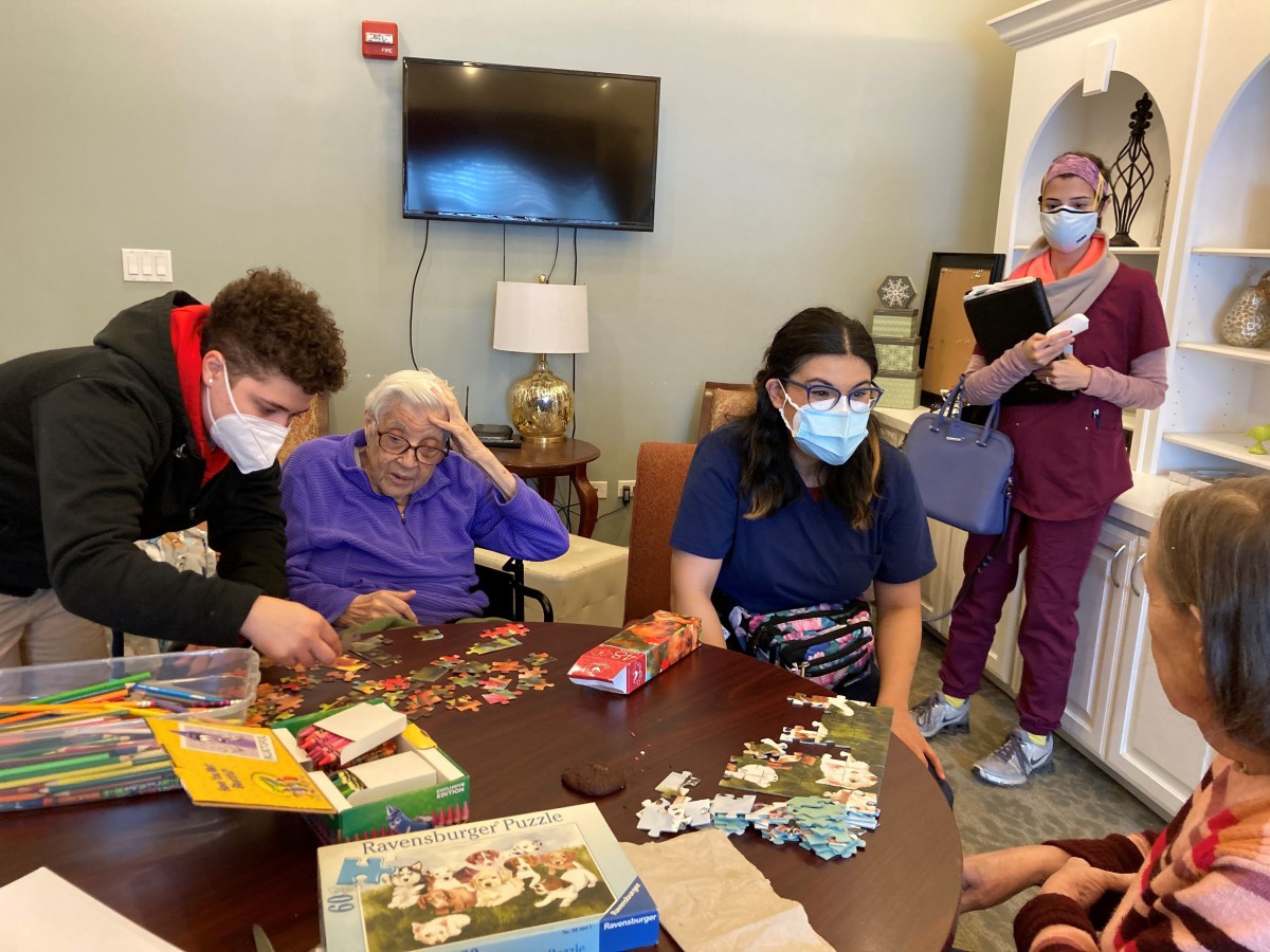 A group of people involved in a puzzle activity at an elderly care facility.