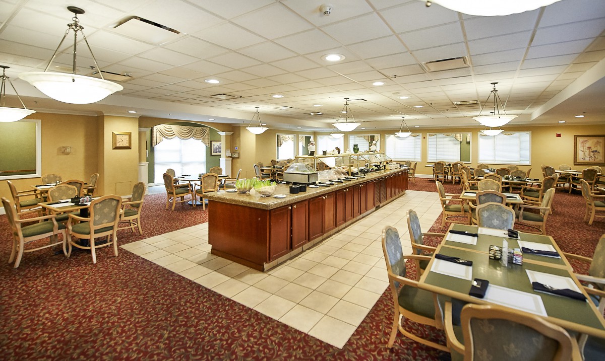 An empty cafeteria with a buffet setup and seating arrangement.