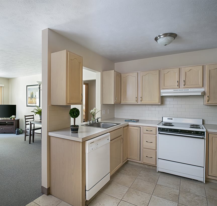 A cozy apartment kitchen featuring beige cabinets and white appliances.