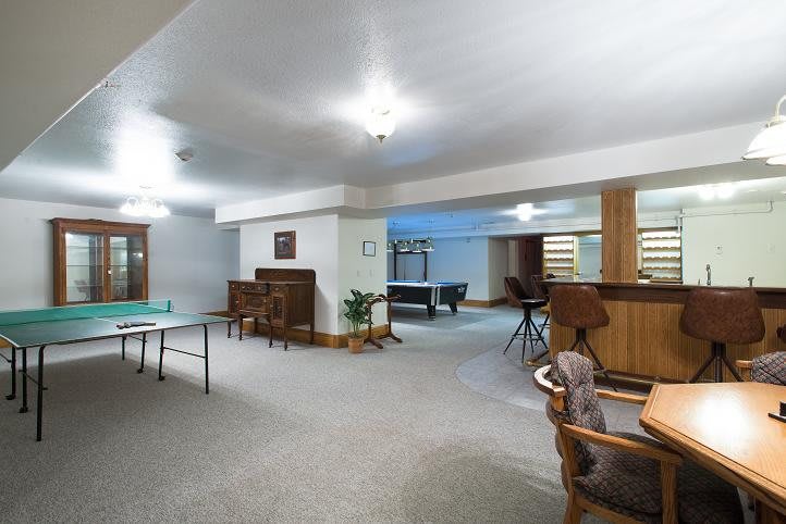 A spacious basement recreation room featuring a table tennis setup and a cozy bar area.