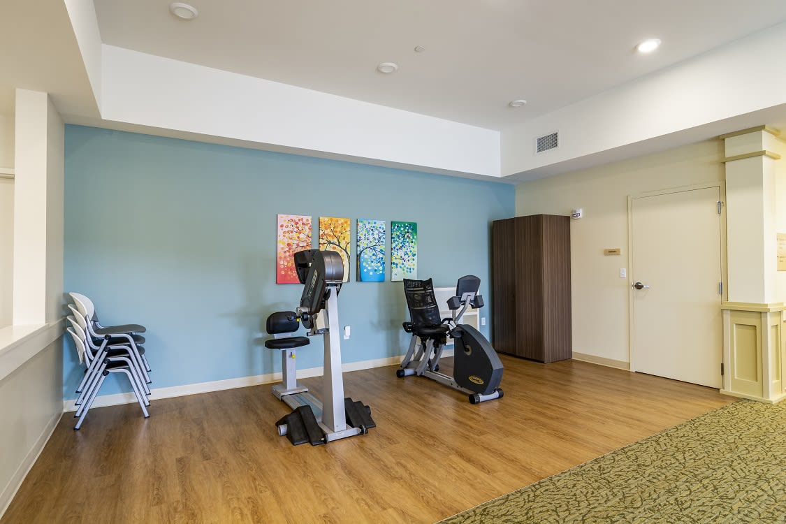 A small gym room with stationary bikes and a wooden floor.