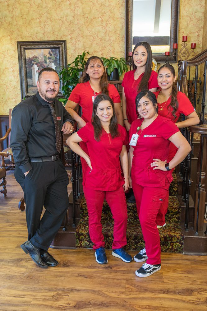 A team of five people posing together indoors, with four wearing red uniforms.