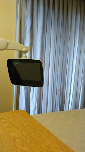 A dental monitor is mounted on an adjustable arm in a clinic setting.