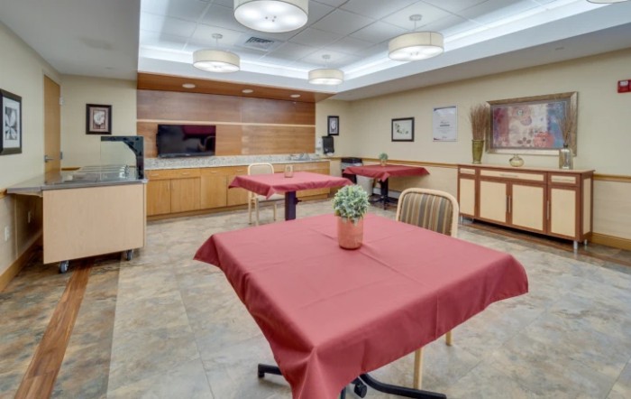 A modern dining area with tables covered in red tablecloths and contemporary lighting.