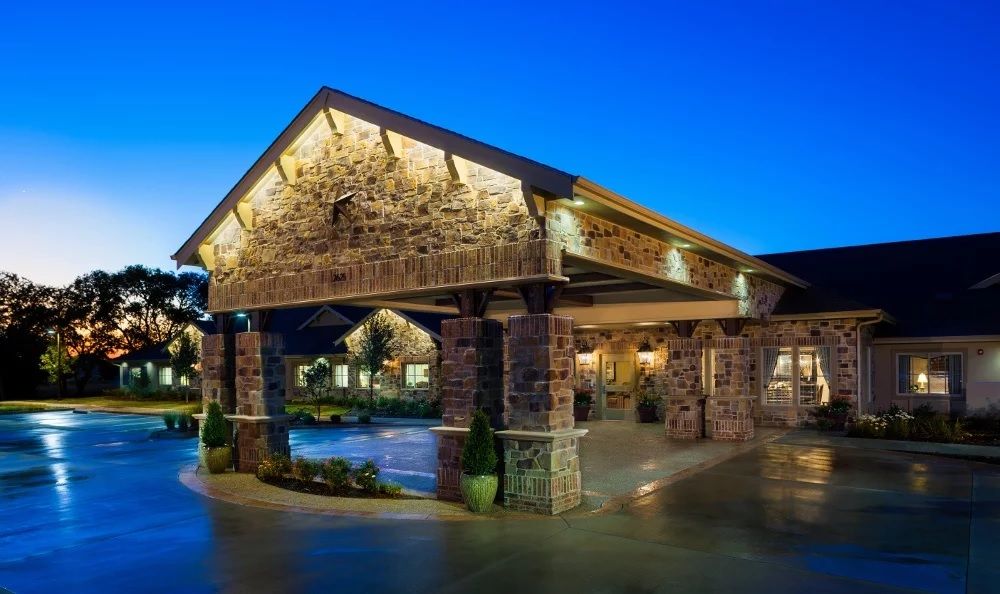 Illuminated building entrance at dusk with stone architecture.