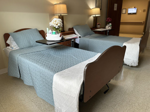A view of a patient room featuring two hospital beds, each with decorative elements and warm lighting.