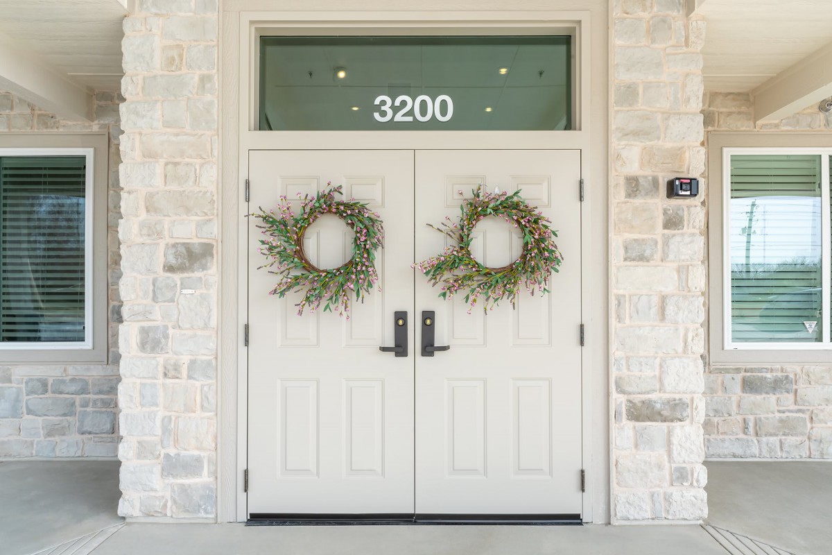 A set of double front doors adorned with wreaths, featuring the house number 3200 above.