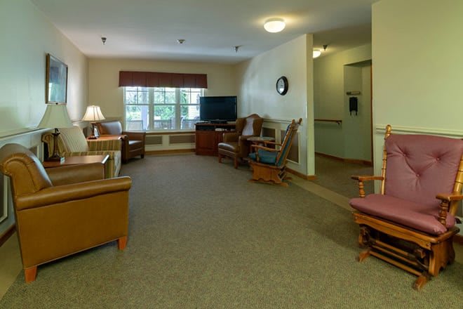 A cozy living room with comfortable seating, a television, and a large window providing natural light.
