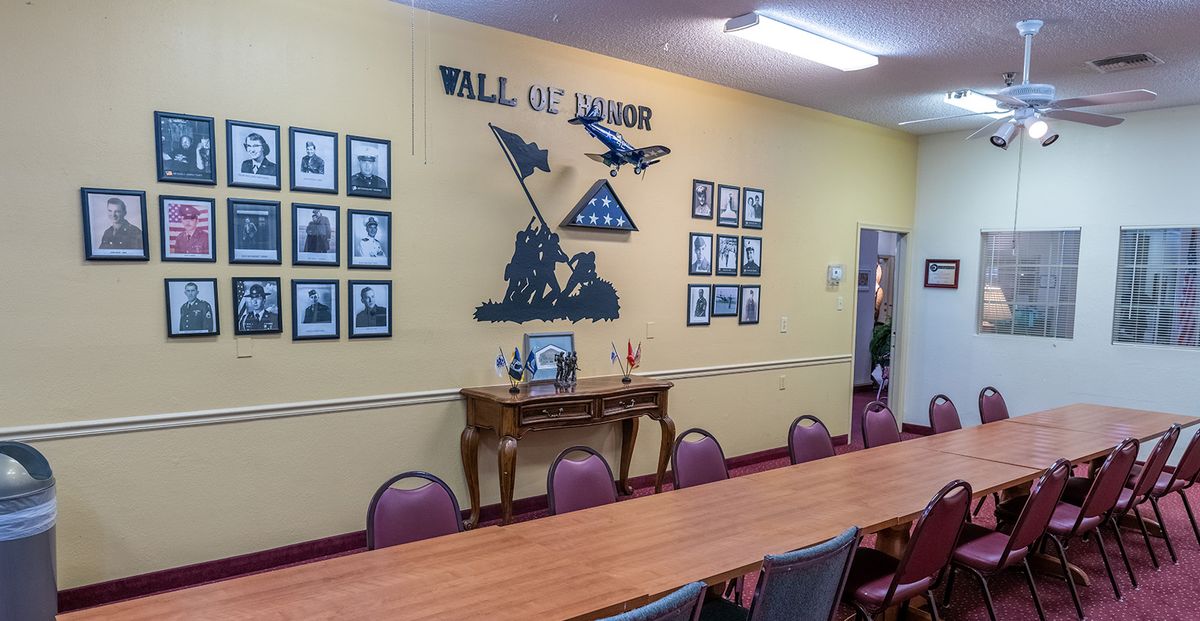 A Wall of Honor featuring military tribute photos and decor in a meeting room.
