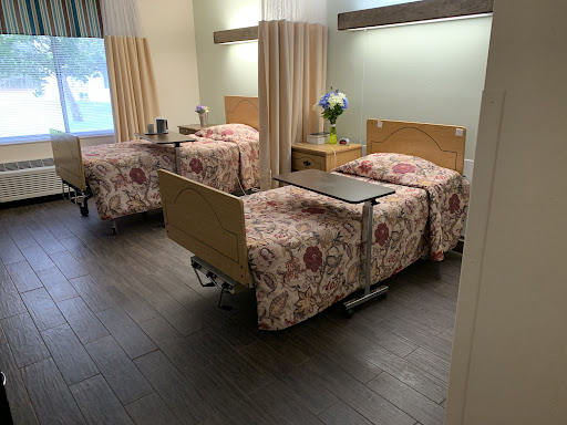 A view of a hospital room with two neatly made beds and a small table.