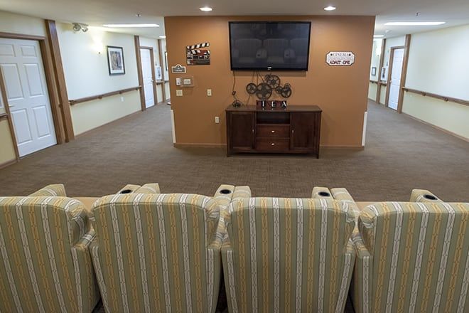 A cozy seating area with striped chairs facing a wall-mounted television in a well-lit room.
