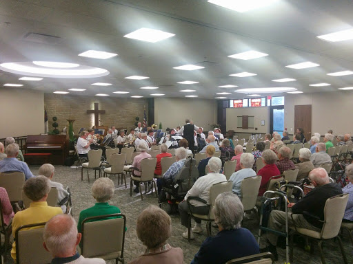 A community gathering of seniors enjoying a presentation in a spacious hall.