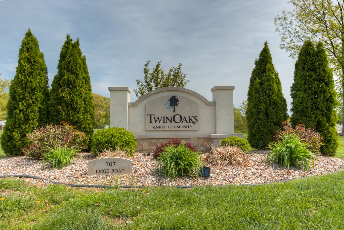 Entrance sign for Twin Oaks subdivision surrounded by landscaping and trees.