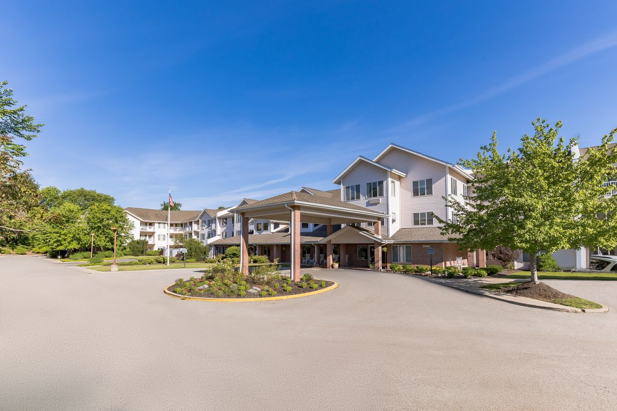 A view of a residential building with a driveway and landscaped entrance under a clear blue sky.