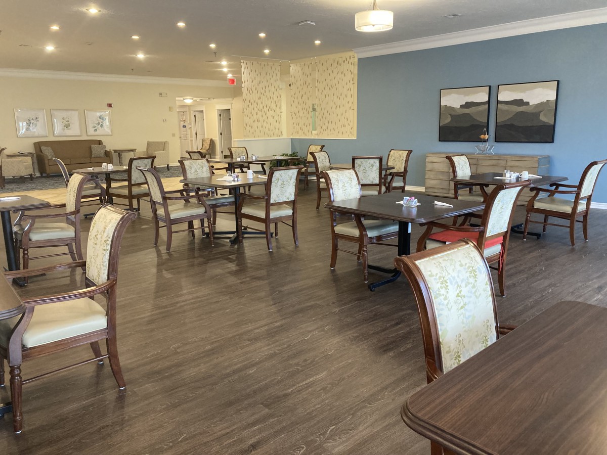 A spacious dining area with multiple tables and chairs, featuring elegant decor and lighting.
